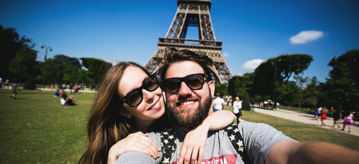 Romantic couple making selfie in front of Eiffel Tower while