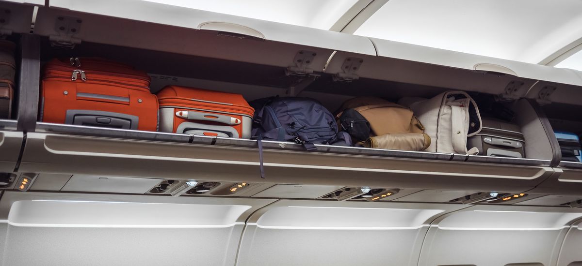 Luggage shelf with luggage in an airplane. Aircraft interior. Travel concept.