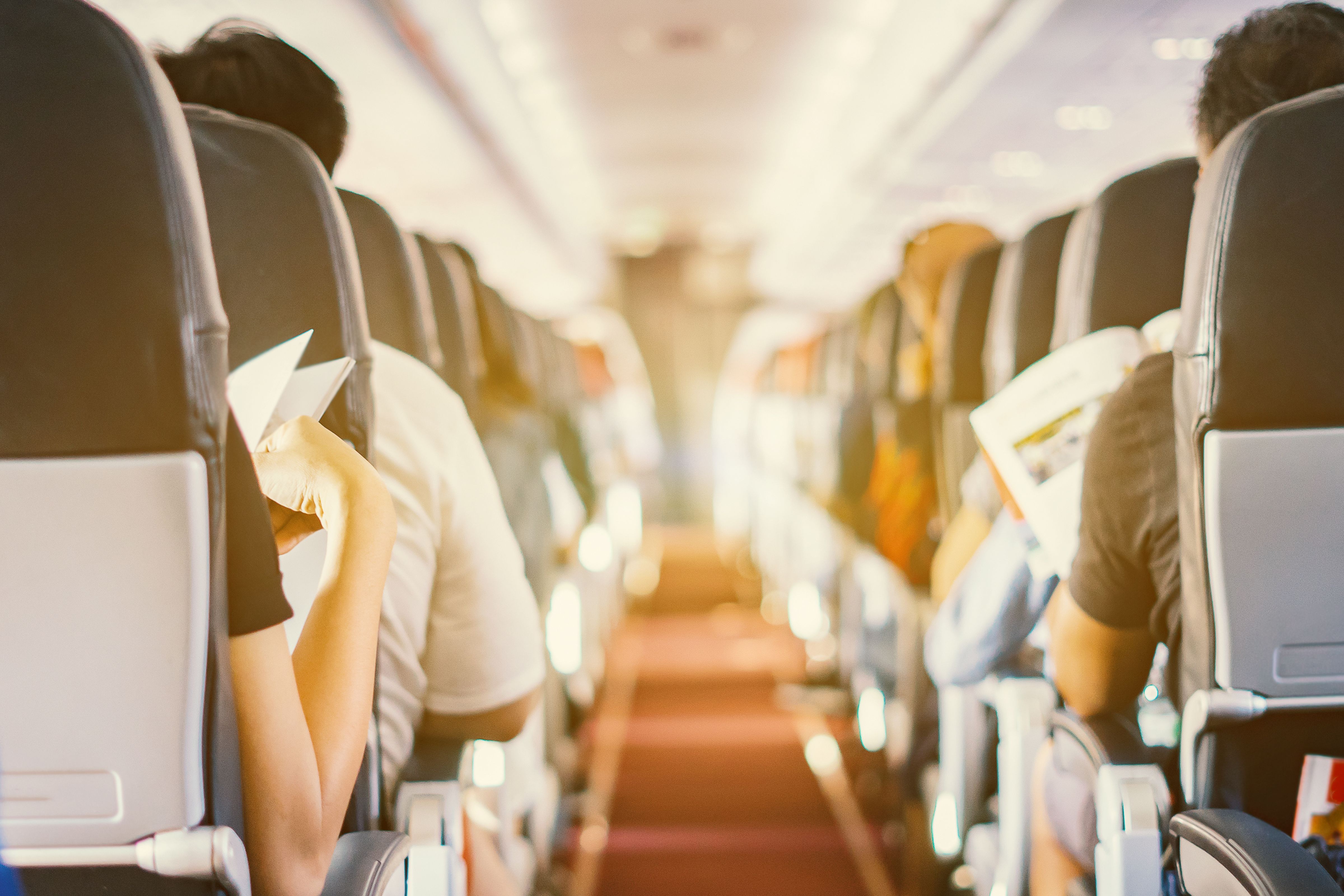 passenger seat, Interior of airplane with passengers sitting on seats and stewardess walking the aisle in background. Travel concept,vintage color,selective focus