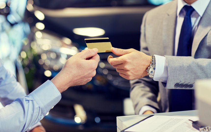 customer giving credit card to car dealer in salon