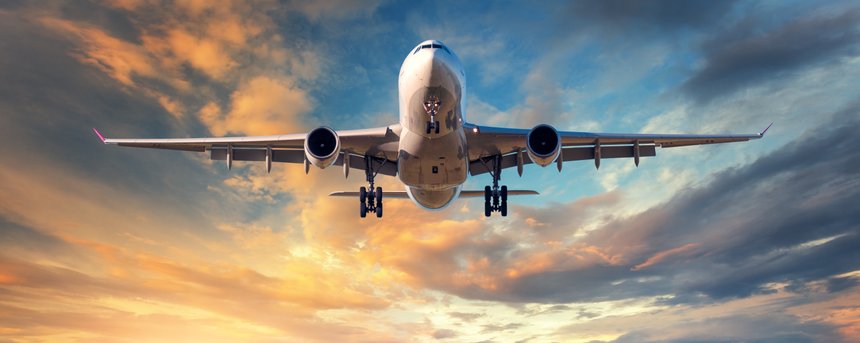Landing airplane. Landscape with white passenger airplane is flying in the blue sky with clouds at colorful sunset. Travel background. Passenger airliner. Business trip. Commercial aircraft. Concept