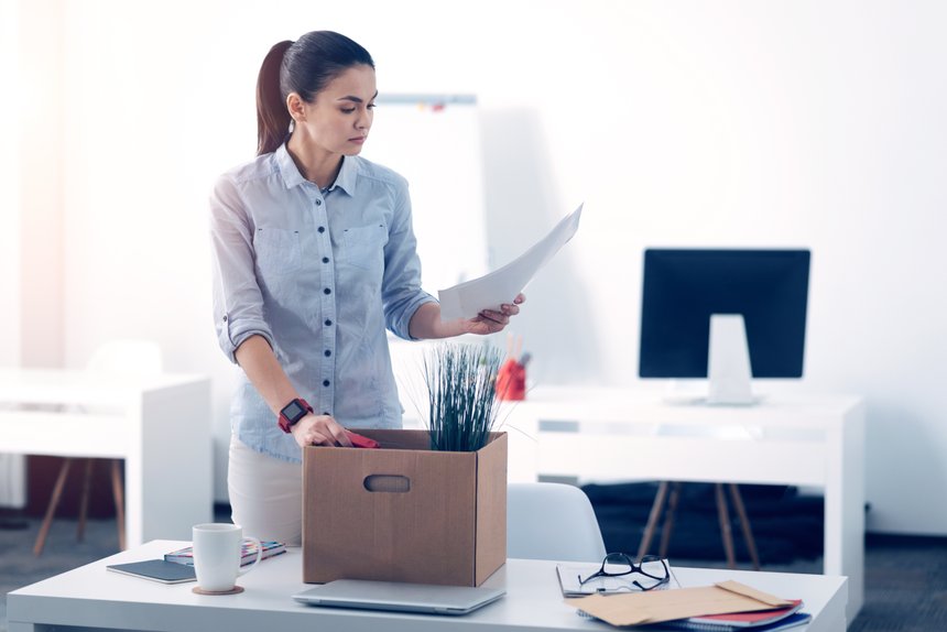 Young employee packing her stuff in box while leaving work