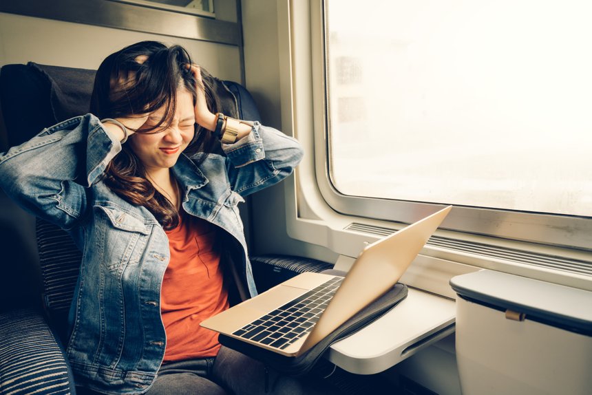 Asian college girl frustrated with laptop on the train, warm lig