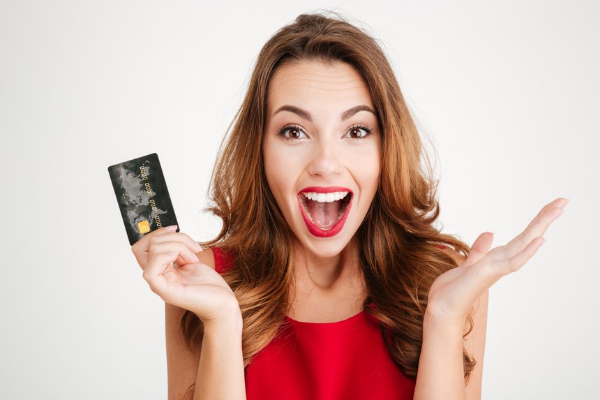 Happy excited amazed young woman holding credit card
