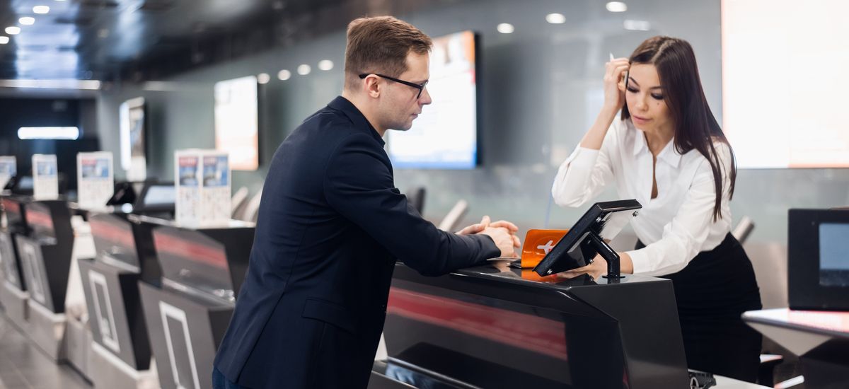 Staff At Airport Check In Desk Handing Ticket To Businessman