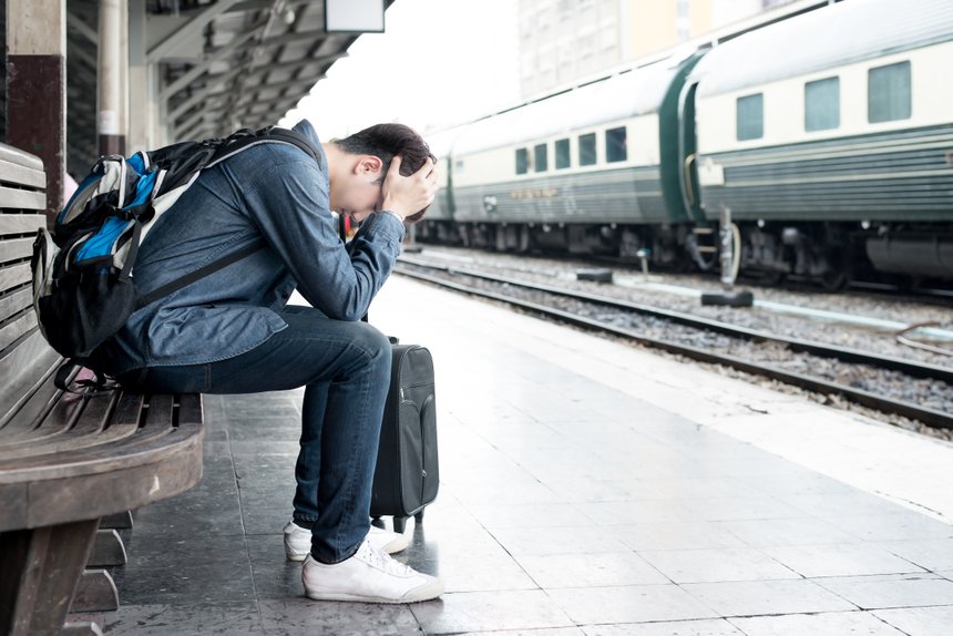 Asian depressed traveler waiting at train station after mistakes