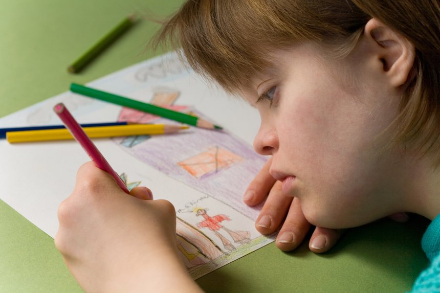 Close up of a girl with down syndrome drawing.