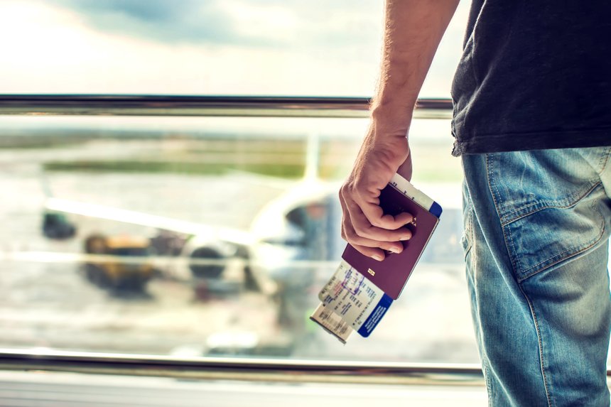 Closeup of man holding passports and boarding pass at airport. Traveling concept