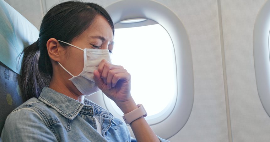 Woman feeling unwell and wearing face mask on plane