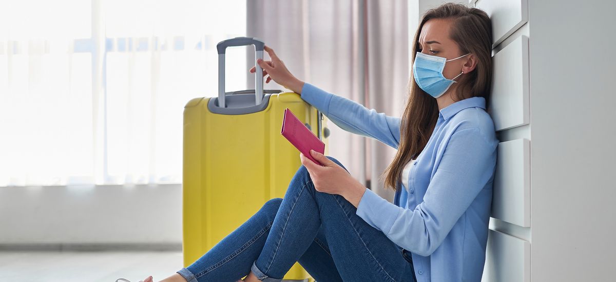 Woman traveler in medical protective mask affected by flight delay and cancelled travel and vacation. Travel ban and troubles due to coronavirus outbreak and covid ncov virus epidemic