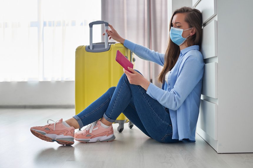 Woman traveler in medical protective mask affected by flight delay and cancelled travel and vacation. Travel ban and troubles due to coronavirus outbreak and covid ncov virus epidemic
