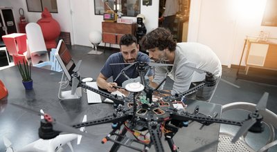 Engineer and technician working together on drone in office