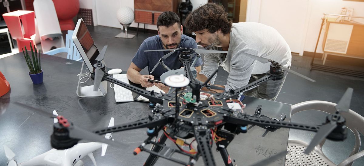 Engineer and technician working together on drone in office