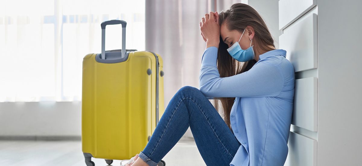 Frustrated woman traveler in protective mask affected by flight delay and cancelled travel and vacation. Travel ban and problems due to coronavirus outbreak and covid ncov virus epidemic