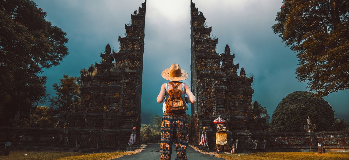 Tourist woman with backpack at vacation walking through the Hindu temple in Bali in Indonesia