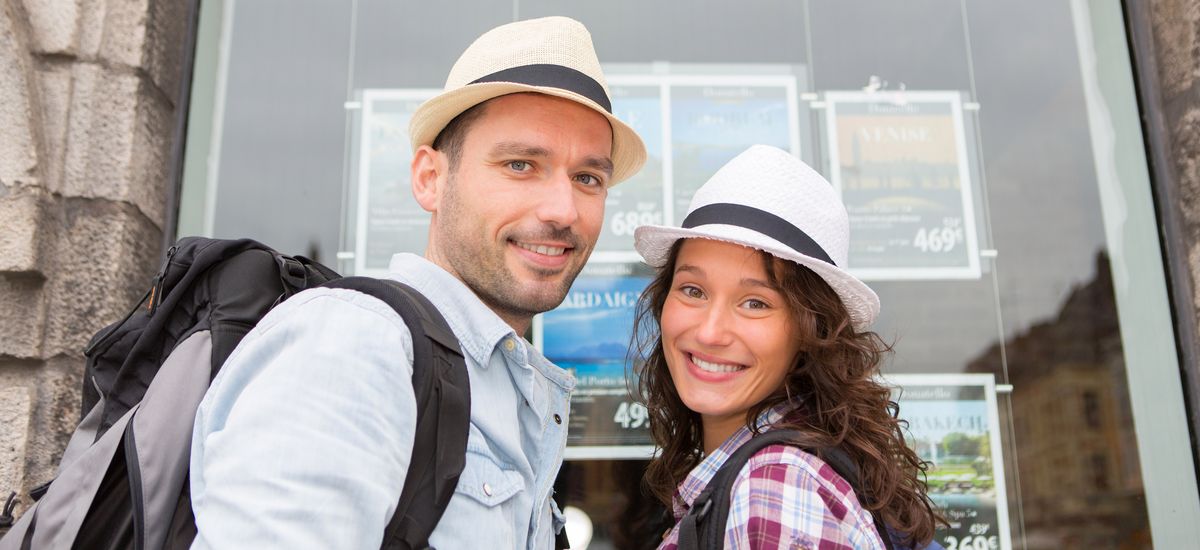 Young happy couple in front of travel agency