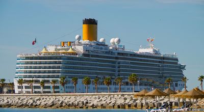 Costa Cruises cruise ship or cruiseship liner Costa Deliziosa in port of Malaga with with sandy beach and palm trees in the Mediterranean