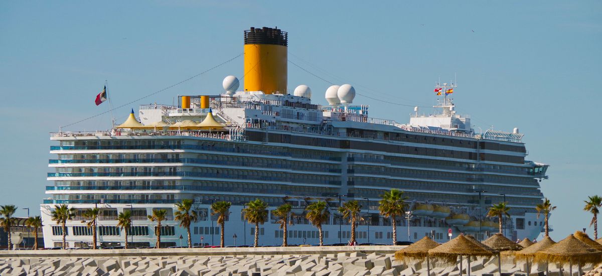 Costa Cruises cruise ship or cruiseship liner Costa Deliziosa in port of Malaga with with sandy beach and palm trees in the Mediterranean