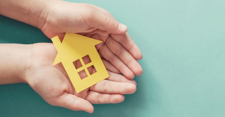 hands holding paper house, family home, homeless housing and home protecting insurance concept, international day of families, foster home care, homeschooling, social distancing