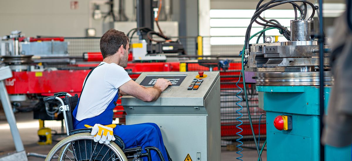 disabled worker in wheelchair in factory and colleague