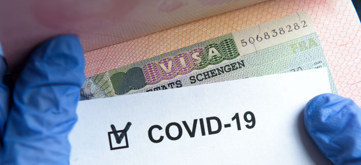 COVID-19 coronavirus pandemic and travel concept, positive mark COVID-19 and Schengen Visa stamp. Passport control of tourists with coronavirus check.