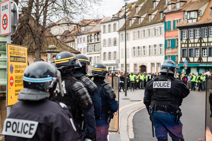 Rear view of police officers securing the zone in frong of the Yellow vests movement protesters on Quai des Bateliers street