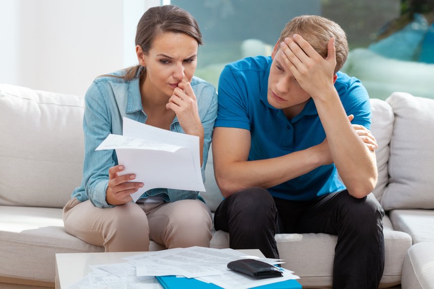 Stressed married couple looking frustrated, having no money to pay off their debts, managing family budget together