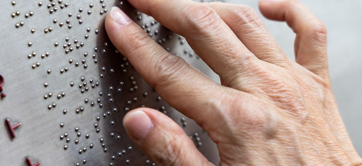 Finger reading braille tactile on public park message board