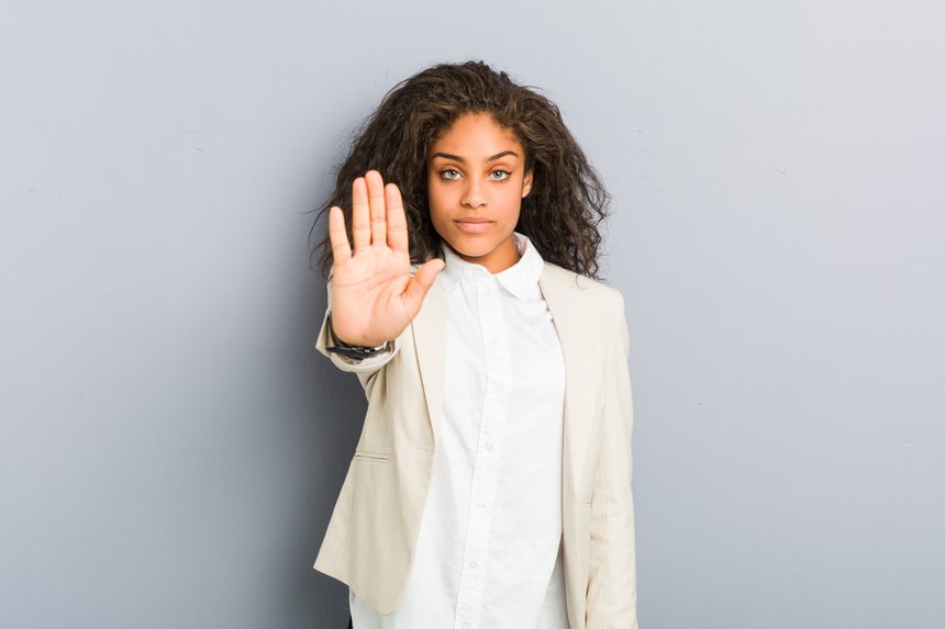 Young african american business woman standing with outstretched hand showing stop sign, preventing you.