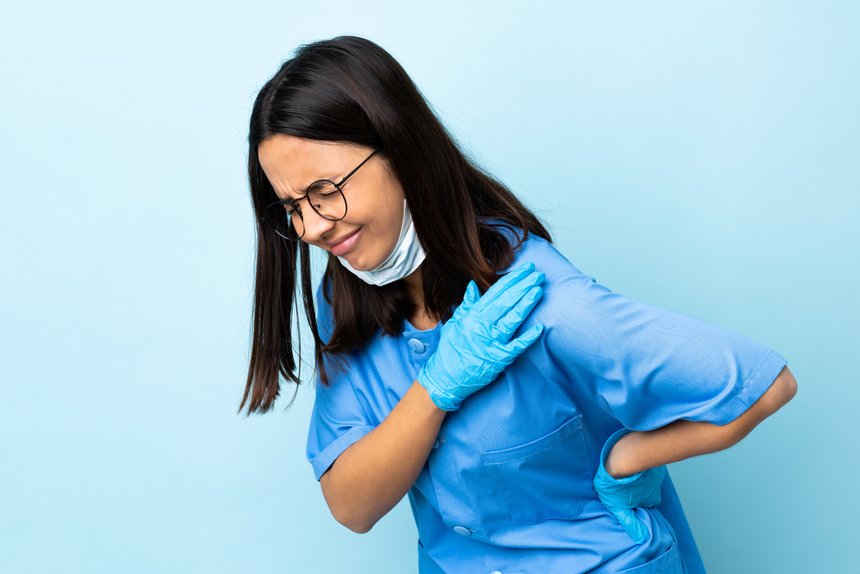 Surgeon woman over isolated blue background suffering from pain in shoulder for having made an effort