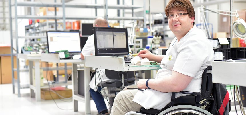 Rollstuhlfahrer am Arbeitsplatz in einer Fabrik zur Montage von