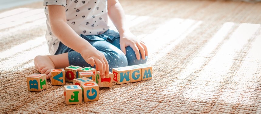 child plays with wooden blocks with letters on the floor in the 