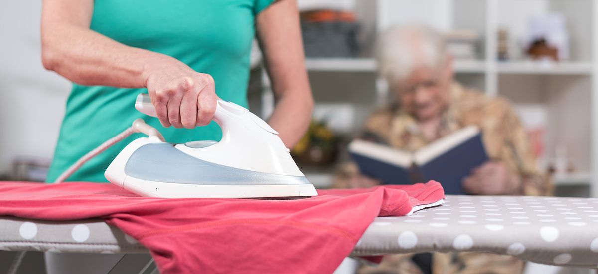 Home helper ironing clothes for an old woman