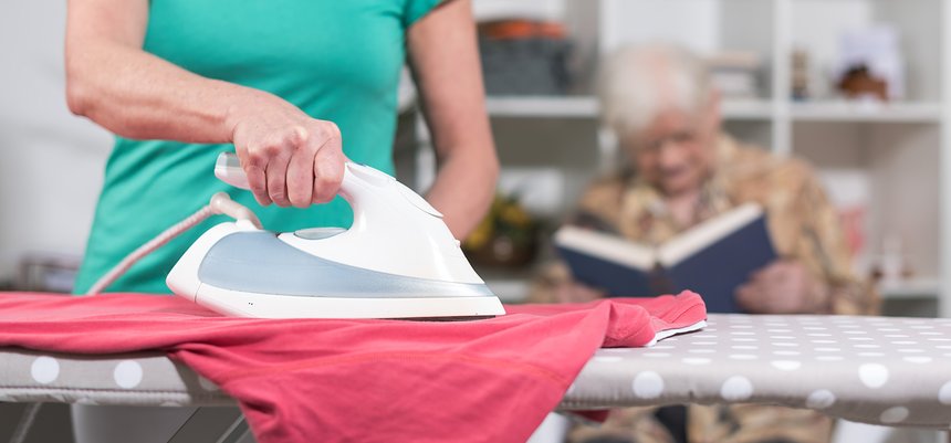 Home helper ironing clothes for an old woman
