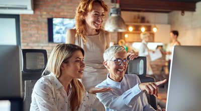 Two younger women colleagues being mentored by senior successful