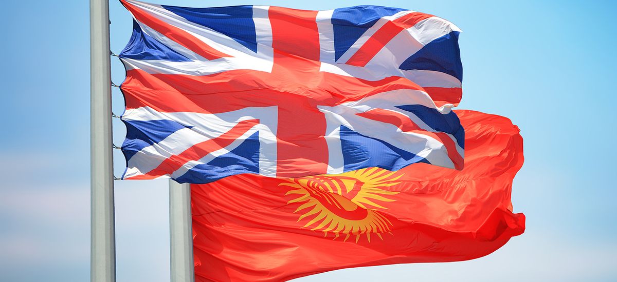 British and Kyrgyz flags against the background of blue sky