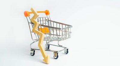 A supermarket cart and a wooden arrow down on a white background