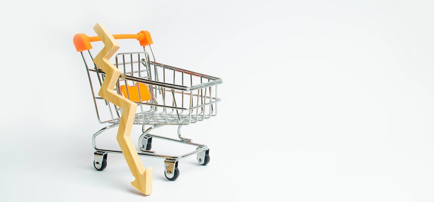 A supermarket cart and a wooden arrow down on a white background
