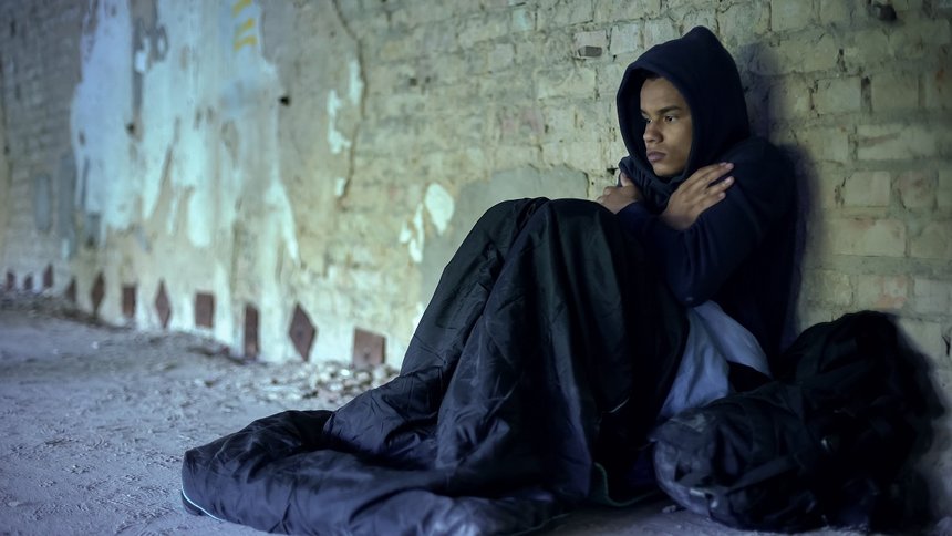Upset homeless teenager wearing hoodie, feeling cold, indifferen