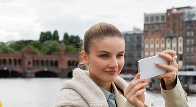 happy young woman taking photo on smartphone on street in Berlin
