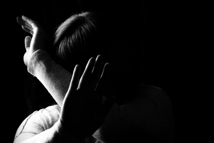 Black and white portrait of a woman hiding her face with hands.