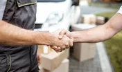 Delivery men shaking hands with a client while delivering goods outdoors, close-up on hands