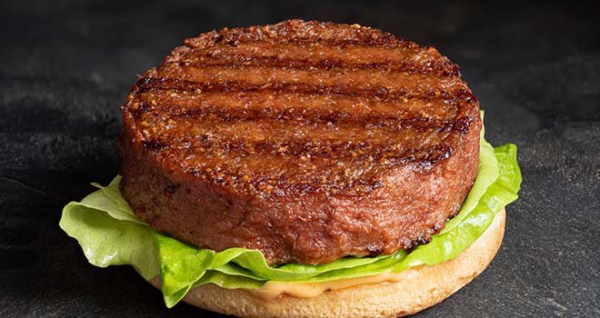 Freshly grilled plant based burger patty on bun with lettuce and