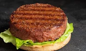 Freshly grilled plant based burger patty on bun with lettuce and