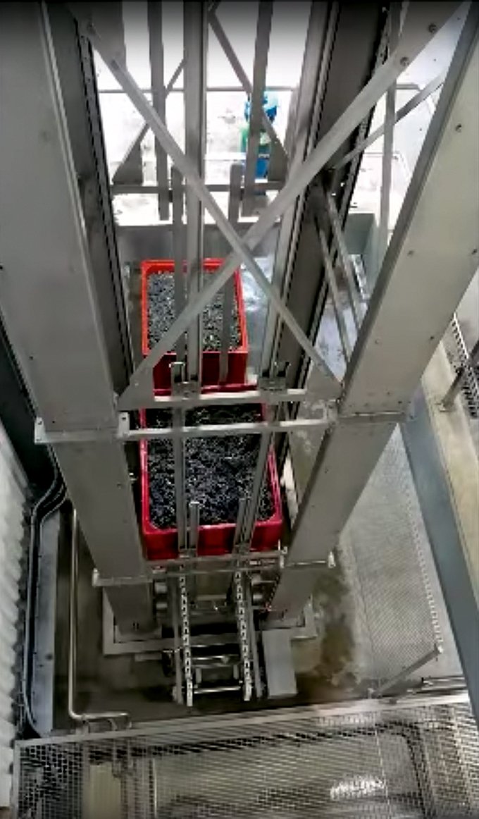 Les caisses-palettes montent par un « ascenseur » pour atteindre les pressoirs.