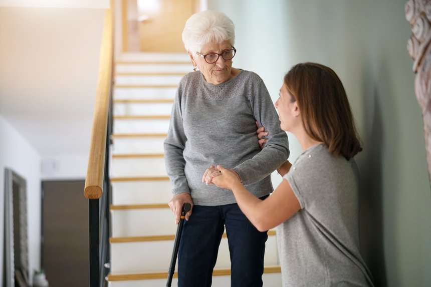 Homecare helping elderly woman going down the stairs