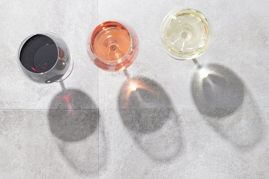 Red, white and rose wine in wine glasses isolated on concrete background with copy space. Top view.