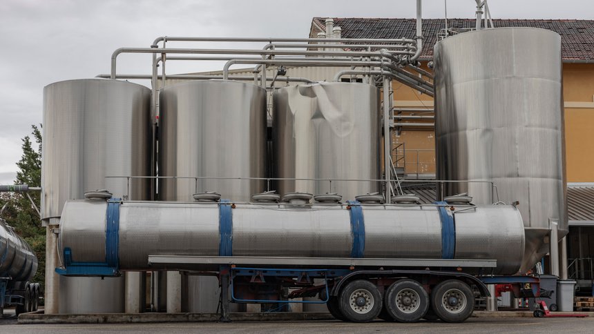 Stainless steel wine tanks and wine tanker waiting outside a factory