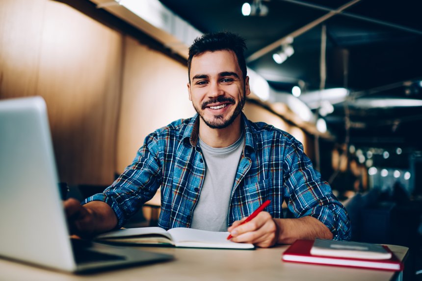 Portrait of cheerful male student enjoying learning in coworking