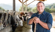 male farmer posing against background of cows in stall